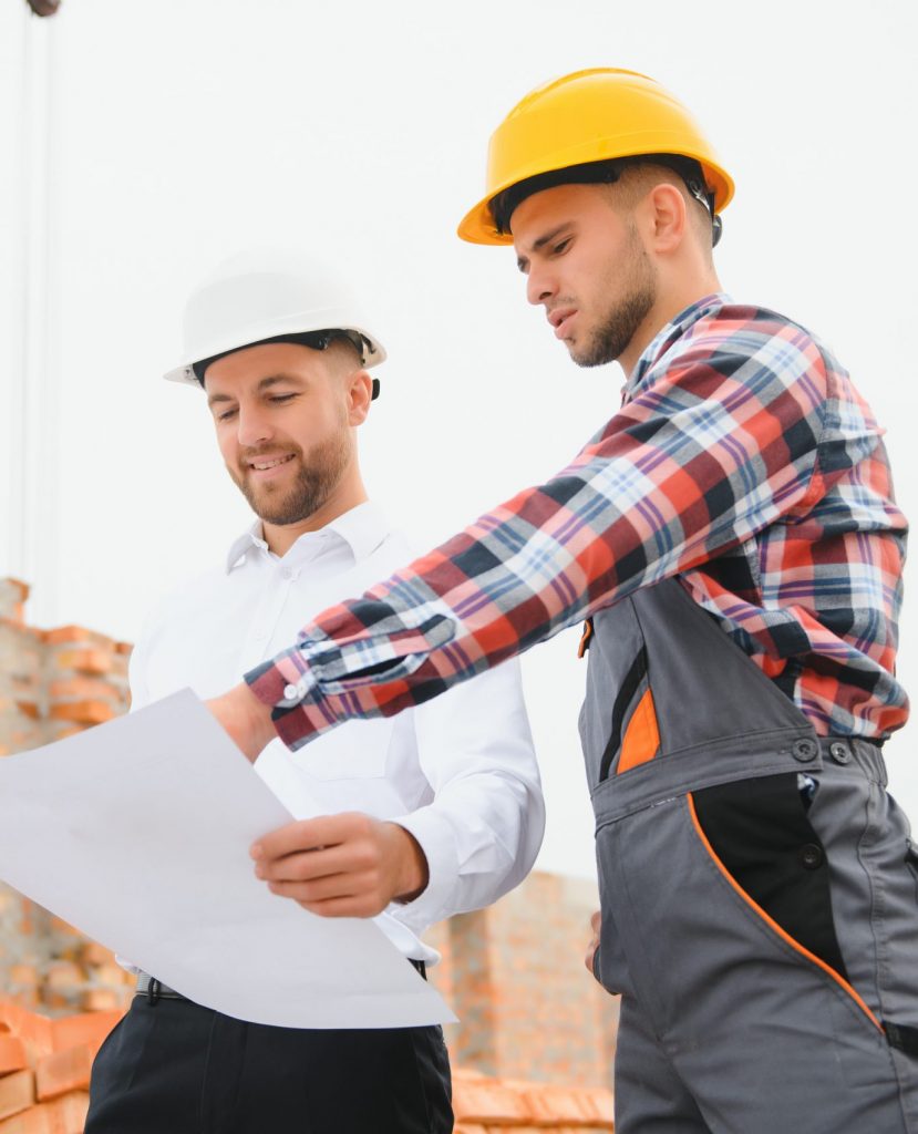 engineer architect with hard hat and safety vest working together in team on major construction site